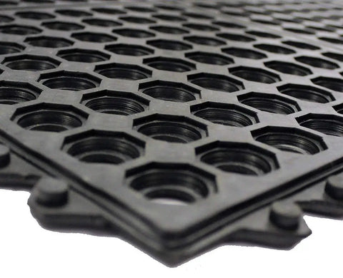 Close-up of an interlocking rubber floor mat with drainage holes, non-slip surface for indoor and outdoor use, 36 inch square tile.
