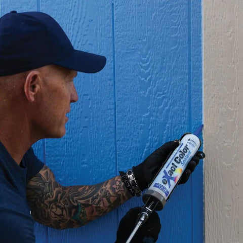 Person using Exact Color Custom Colored Caulk DIY Kit with 9.5 Ounce Cartridge and 30 ml Syringe on blue siding.