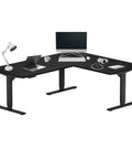 Rock Solid Electric Corner Standing Desk L Shaped 70 By 55 Inch Workstation with black steel frame and a modern workspace setup.