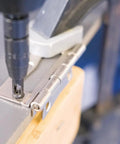 1/4 in drill bit in a drill engaged with a metal hinge plate