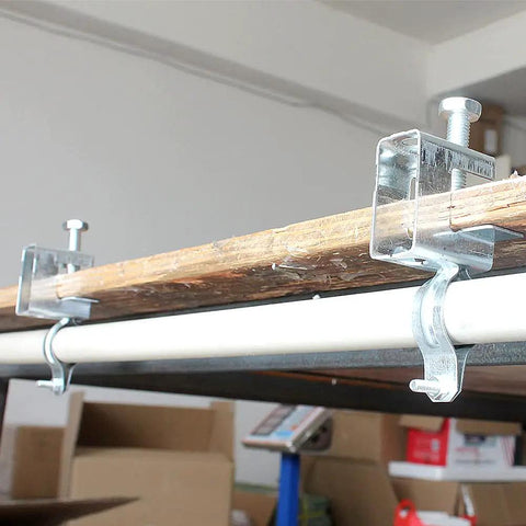 Beefy Heavy Duty Galvanized Steel Cable Clamps Set securing pipes to a wooden beam indoors
