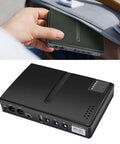 Zero Stress DC UPS Backup Power Supply Providing 18W Multi Output For Routers And Cameras US Plug compact backup power unit held in hand.