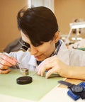 Watchmaker using Pro Grade Watch Demagnetizer Tool For Mechanical Timepieces 110V Degauss Device with a mechanical watch on the table