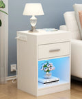 Ultra Sleek White Nightstand Packs A Rapid Charging Hub And Ambient Led Lighting While Guarding A Legit Hidden Safe For Stashing Cash And Electronics Plus Extra Power Outlets with floral decor and lamp.