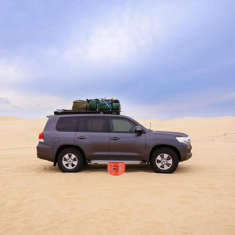 BotaBay 4 Ton Off-Road Air Jack With 8800 Lbs Capacity Inflatable Soft Jack for Truck and SUV on sandy terrain next to a grey vehicle.