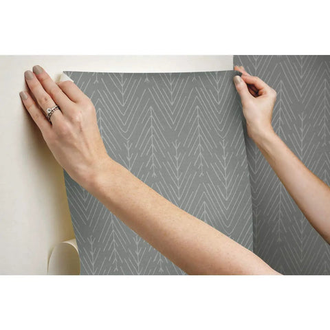 Hands applying Charcoal Gray Twig Hygge Herringbone Peel And Stick Wallpaper 20.5 Inches Wide 16.5 Feet Long Removable No Residue