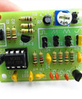 Close-up of a green electronic circuit board showcasing resistors, capacitors, and a NE555 timer chip, used in electronics projects.