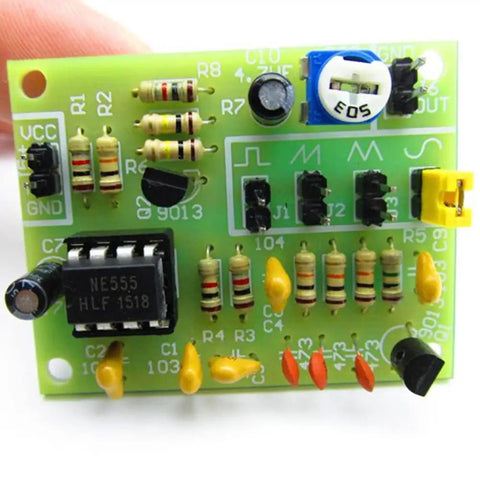 Close-up of a green electronic circuit board showcasing resistors, capacitors, and a NE555 timer chip, used in electronics projects.