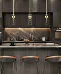 Modern Brass Pendant Light Over Kitchen Island With Clear Glass Shade in a sleek kitchen setting, adjustable rods visible