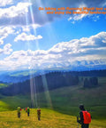 Scenic mountain landscape with people hiking in grassy field under blue sky with white clouds.