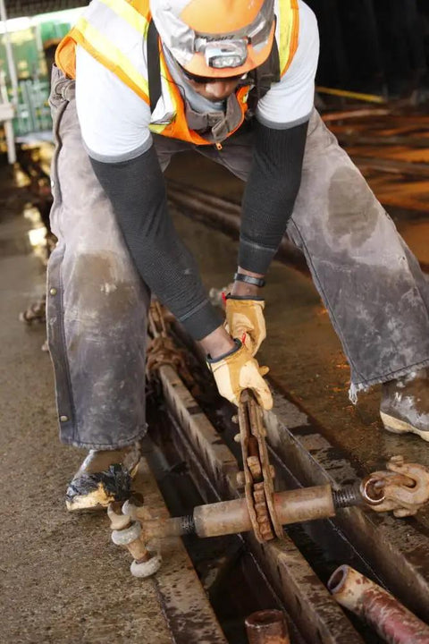 Worker using Flame And Arc Resistant Leather Driver Gloves With Durahide Leather, Water Repellent Finish, in industrial setting.