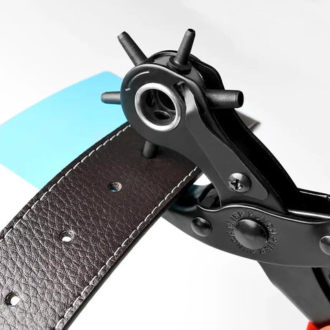 Close-up of Rotating Leather Hole Punch Kit with six-diameter steel head punching a black leather belt in a DIY setup.