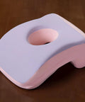 Violet cooling memory foam face down pillow with ice cloth cover showing cutout for face support on a wooden table.