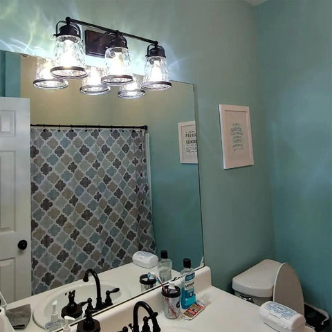 Black 3 Light Industrial Vanity Sconces With Hammered Glass Shades above bathroom mirror, vintage rustic farmhouse style.