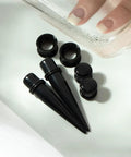 Starter Pack For Ear Stretching 50 Piece Kit With 14G To 00G Acrylic Tapers And Plugs Silicone Tunnels close-up on black pieces
