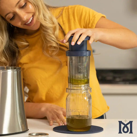 Woman using BPA-Free Reusable Oil And Butter Filter Press With Plunger And Brush, Mess-Free Infused Oil Strainer over a jar.