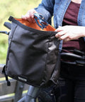 Person holding open Alpha Handlebar Bag 6 Liter for City Commutes and Bike Tours, Weatherproof Messenger With Roll Top And Tech Pocket