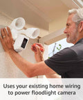 Ring Floodlight Cam Wired Plus outdoor security camera in white being installed on exterior wall with dual floodlights