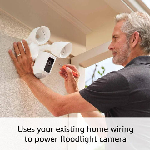 Ring Floodlight Cam Wired Plus outdoor security camera in white being installed on exterior wall with dual floodlights