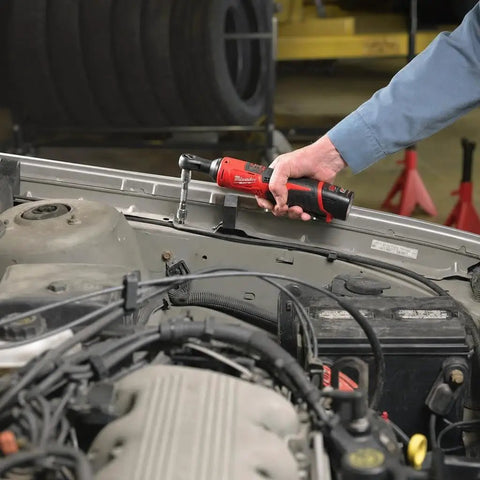 Heavy Duty M12 Three Eighth Drive Cordless Ratchet Battery Operated Power Tool Boasting Kickass Torque and Rock Solid Build being used in a garage.