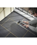Person using Pro Grade Corded Oscillating Multi Tool Kit 120V 3.5 Amp Power, Reconditioned on floor tiles for cutting