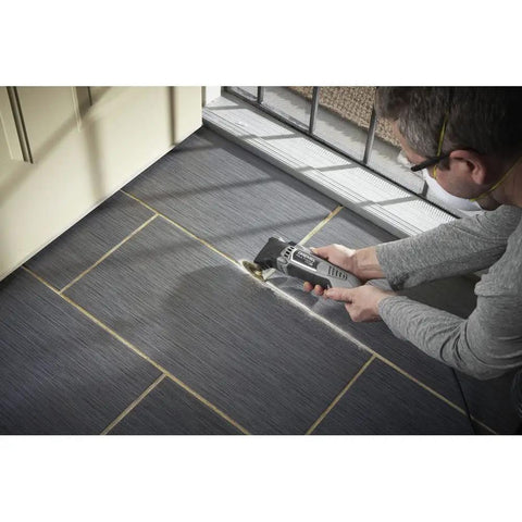 Person using Pro Grade Corded Oscillating Multi Tool Kit 120V 3.5 Amp Power, Reconditioned on floor tiles for cutting