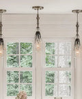 Kitchen with black L-shaped brackets supporting white shelves, displaying dishes and decor items, under pendant lights.