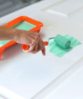 Two Inch Density Foam Paint Roller With Frame For Corner And Trim Jobs in use, applying paint on a white door with paint tray nearby.