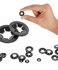M4 internal-tooth star lock washers, steel black finish, 100 pcs close-up with hand holding one