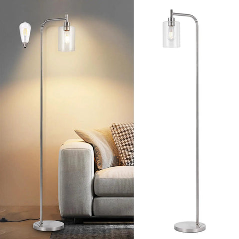 Modern silver floor lamp with curved design and glass shade next to a sofa, lit bulb on the left, unlit on the right.