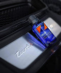 Blue CARPRO CQUARTZ DLUX wheel and trim coating bottle with black cap beside a silver Turbo badge.