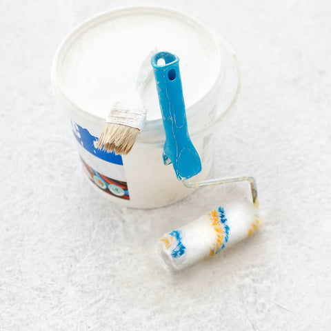 Mini paint roller and brush next to a paint bucket, showcasing Bulk Pack 100 Mini Paint Roller Covers 6 Inch For Quick Home Painting DIY Projects.