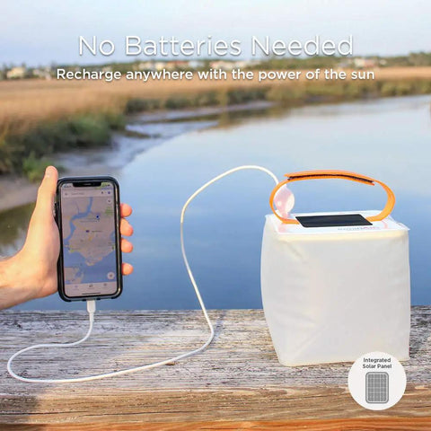 Two In One Solar Camping Lantern And Phone Charger for outdoor adventures with phone connected, near a scenic lake view.