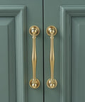 Solid Brass Cabinet Pull And Drawer Knob With Modern Grooved Base Design in Antique Brass Gold on green cabinet doors.