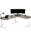 Spacious L Shaped Electric Sit Stand Desk For Home Office Smooth Height Adjustable Workstation With Wide Top Effortless Assembly And Built Tough Steel Frame Ready For Any Grind, featuring laptop and monitor.