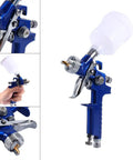 Precision Mini Gravity Feed HVLP Spray Paint Gun With 0.8mm Nozzle And 100ml Cup held in hand, showing detail orientation and nozzle.