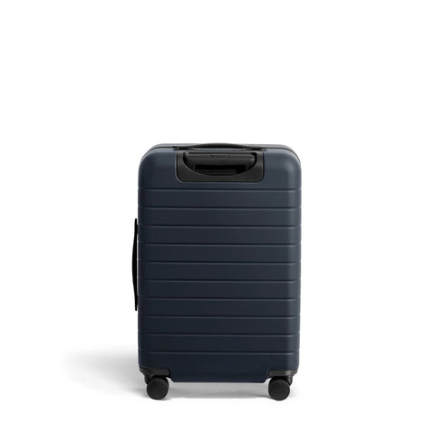 Bigger Carry On Luggage From Away, navy blue suitcase with spinner wheels, TSA lock, durable polycarbonate shell, ideal for travel.