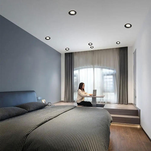 Round Led Recessed Spotlights in a bedroom with slick brushed brass and matte black trim, illuminating a workspace.