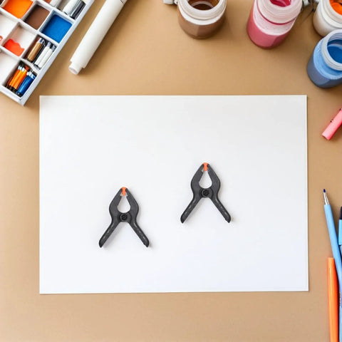 Must-Have 20-Ply Small Spring Clamps Kit For Woodworking And Photography Backdrop Clips Plus Heavy Duty Plastic Cloth Holders Perfect For Crafting, Home Improvement, Studio Work, Office Tasks, And Everyday Organization Adventures. Two small black plastic spring clamps on white paper