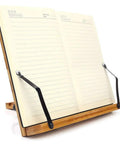 Bamboo Adjustable Book Stand With Tray And Clips holding open notebook, showing front view of foldable reading desk.