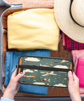 Hands holding Must Have Airplane Cosmetic Bag For Women, cute cartoon aircraft design, in open suitcase with clothes and hat
