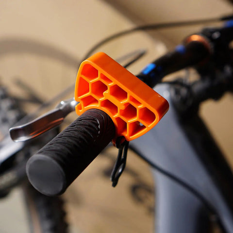 Clip On Bike Stabilizer and 30mm Elevation Tool attached to handlebar for inverted parking, orange plastic with no slip rubber straps.