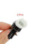 Close-up of two-pin front brake pad wear sensor connector with white housing and black mounting base