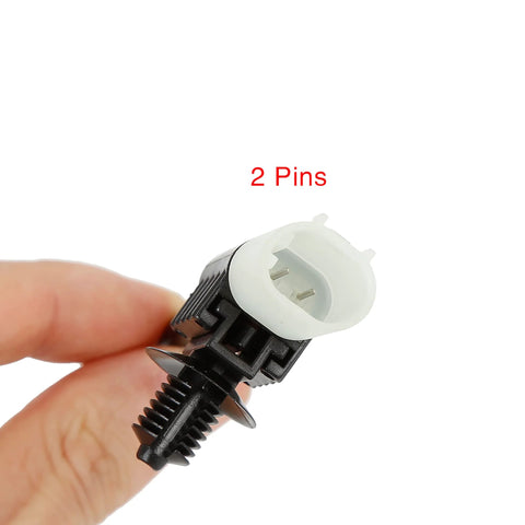 Close-up of two-pin front brake pad wear sensor connector with white housing and black mounting base