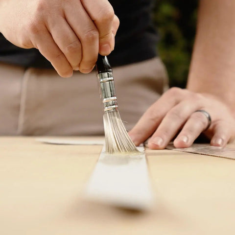 Hella Strong Contact Cement For Wood And Metal Projects Heavy Duty Adhesive For Laminates And Veneers Interior Exterior Bonding Solution That Bonds Like Crazy In A Convenient Three Ounce Tub being applied with a brush.