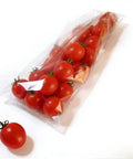 Sleek Compact Horizontal Flow Wrapper Shrink Wrap Sealer featuring dead simple setup and no sweat operation packing fifty to eighty units per minute for deli shops and fresh markets, with sealed cherry tomatoes in a clear wrap.
