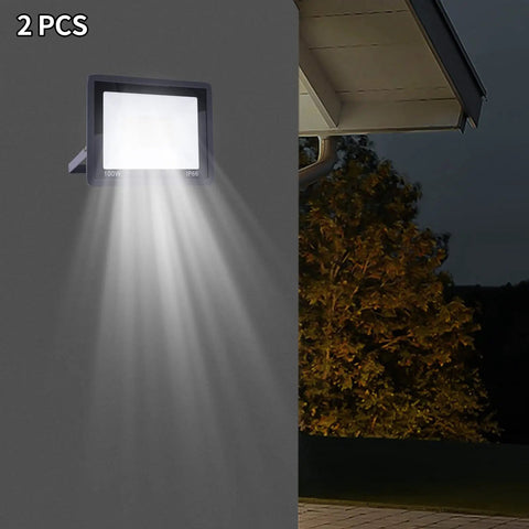LED Work Light 100W 8000LM Flood Light Outdoor IP66 Weatherproof Plug in mounted on wall, casting bright light outdoors.