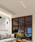 Modern living room featuring Silver Adjustable LED Recessed Spotlight illuminating art, with a cozy couch and wooden window frame.