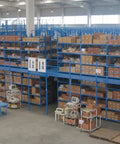 Large warehouse with shelves stacked with boxes and workers packing items in a clean, organized environment.