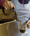 Person pouring coffee wearing Disposable Poly Aprons 28x46 Inches, Individually Wrapped, Waterproof From Neck To Knee